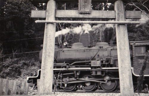 福岡県みやこ町 「 鳥居の間に敷かれた線路の上を列車が走る 」